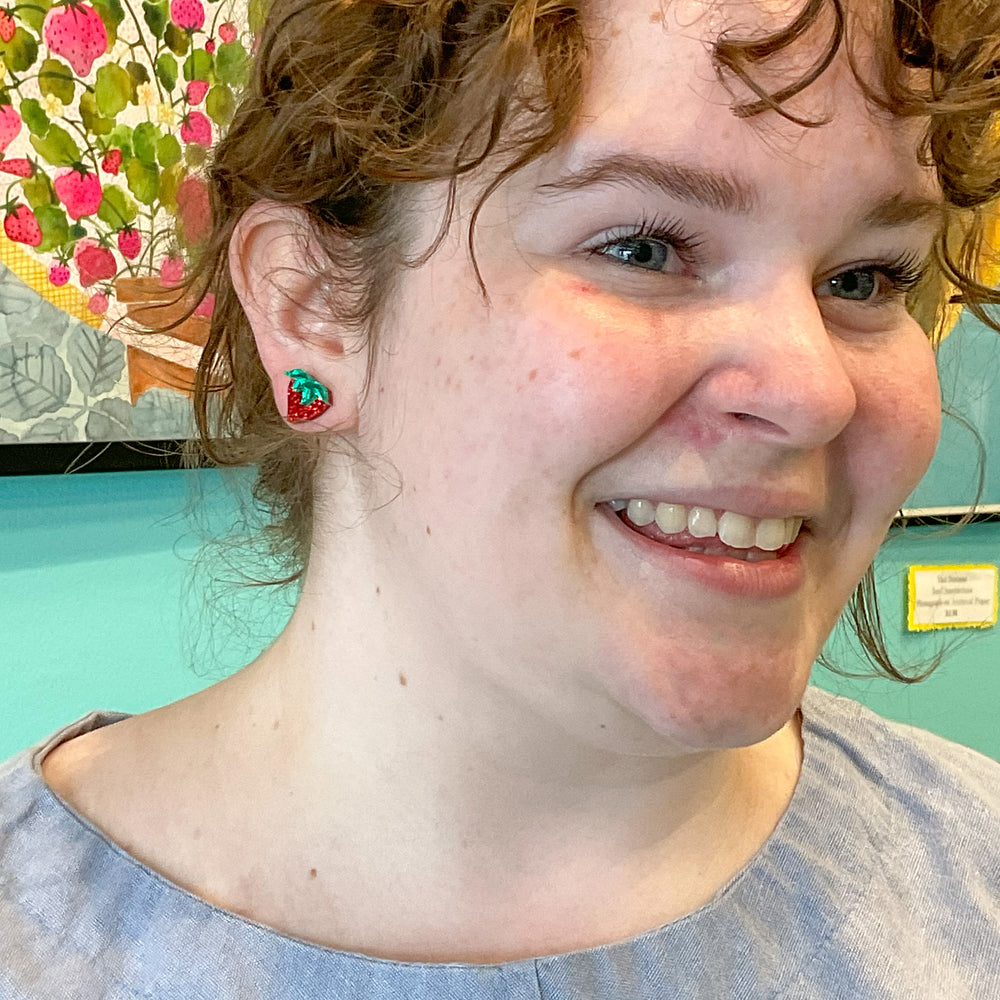 Handmade glitter red strawberry earrings as worn by a model