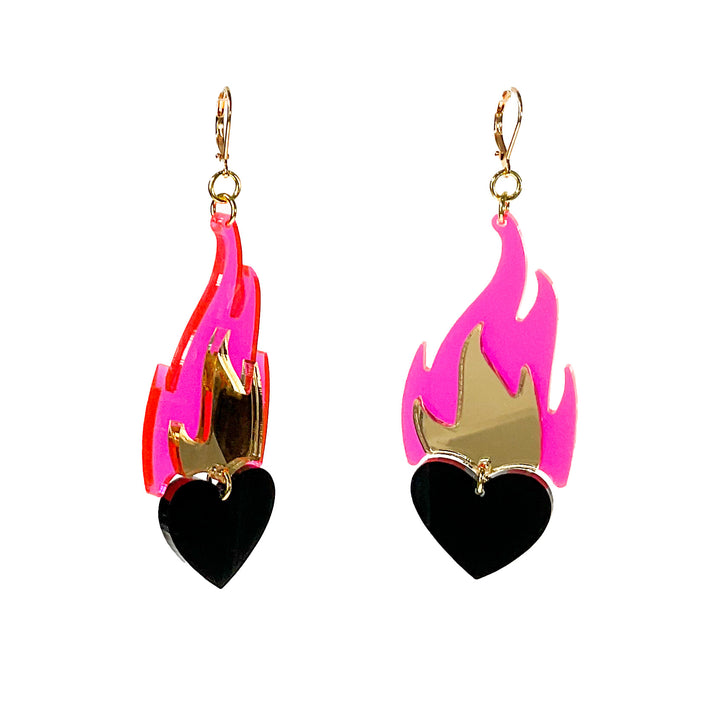 Our handmade Love A La Flambé earrings in neon pink with solid black heart and mirror gold inner flame float in front of a white background.