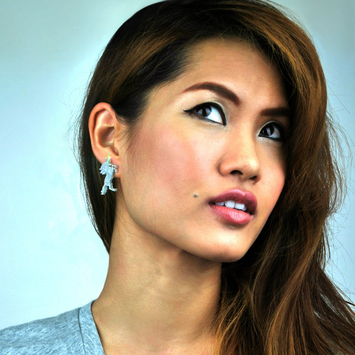 Unicorn earring in glitter hologram on a woman that is looking up. 