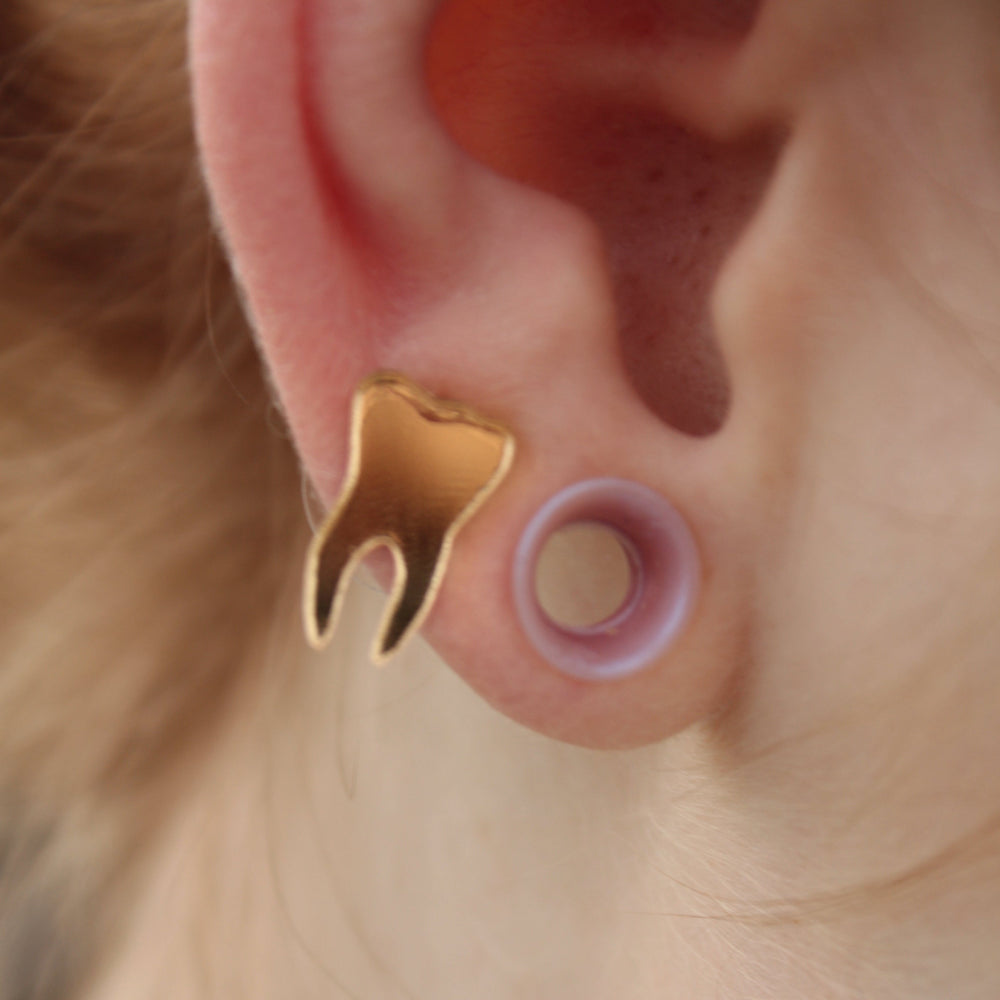 mirror gold teeth earrings on a model who also has tunnels