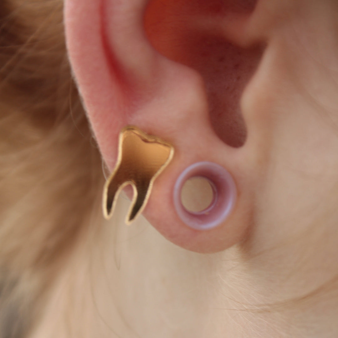 mirror gold teeth earrings on a model who also has tunnels