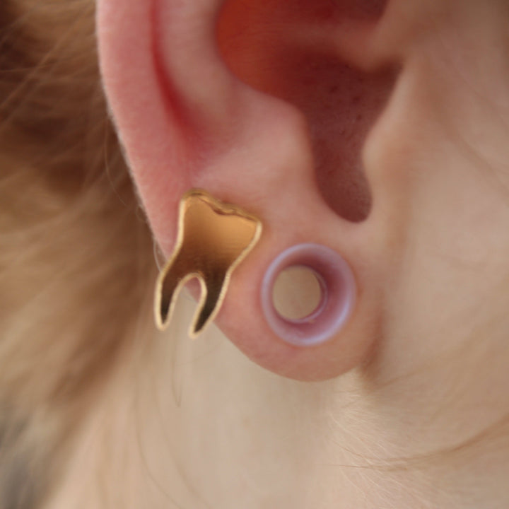 mirror gold teeth earrings on a model who also has tunnels